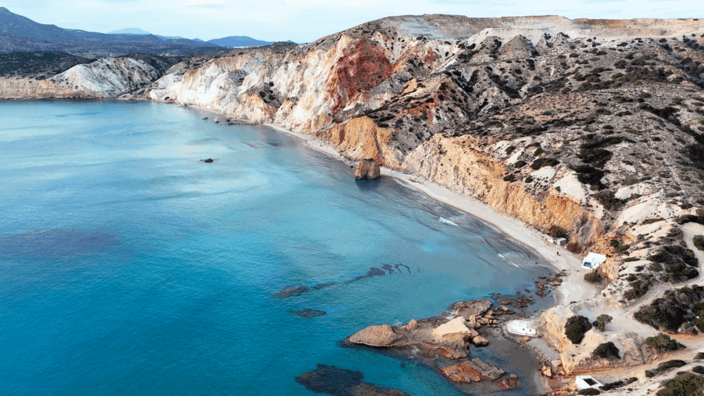 Turquoise shallow water and coloured cliffs at a beach on Milos